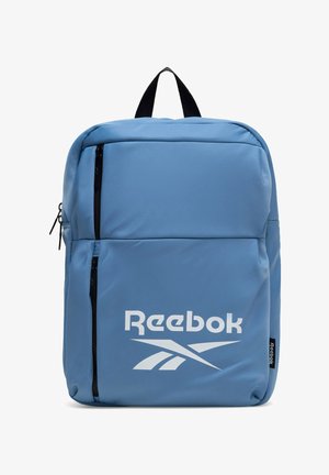 Mochila azul de Reebok con dos bolsillos verticales con cremalleras negras y el logo blanco de Reebok en el bolsillo frontal.
