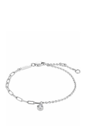 Bracelet délicat en chaîne argentée avec des styles de maillons variés et un petit pendentif en forme de pierre transparente ronde près du fermoir.