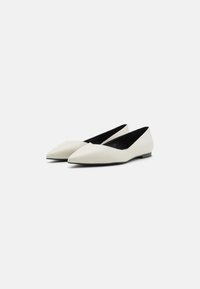 Ballerines blanches en cuir avec un design à bout pointu, forme minimaliste et doublure intérieure noire. Texture lisse avec un talon bas.