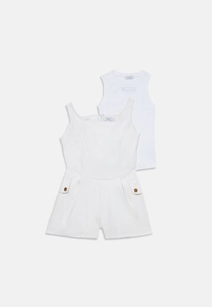 Fehér ujjatlan overál elöl gombos zsebekkel, egy fehér ujjatlan felső fölött, melyen kis logó található a mellrészen.