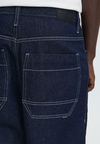 Donkerblauwe denimshorts met twee grote achterzakken met witte stiknaden en een gestructureerde stof. Leren logo-label bij de tailleband.
