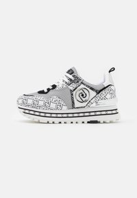 Sneaker sportive con motivo bianco e nero, parte superiore in rete, accentuazione del logo prominente, suola testurizzata e borchie decorative in argento sulla soletta.