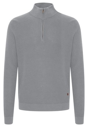 Pilkas megztinis su aukšta apykakle ir pusiau užtrauktuku. Turi šonkačių tekstūrą ir nedidelį logotipo etikete ant apytušio.