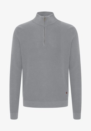 Pilkas megztinis su aukšta apykakle ir pusiau užtrauktuku. Turi šonkačių tekstūrą ir nedidelį logotipo etikete ant apytušio.