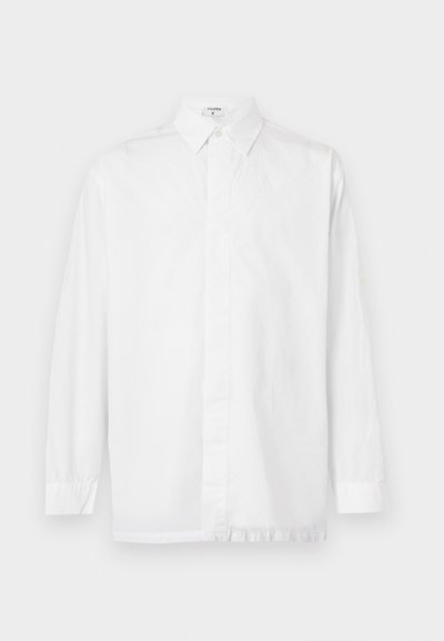 Λευκό πουκάμισο με μακριά μανίκια, μυτερό γιακά και κρυφά κουμπιά, ακουμπισμένο επίπεδα πάνω σε ανοιχτό φόντο.