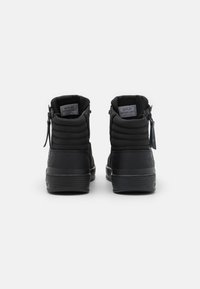 Černé kotníkové boty s prošívaným textilním svrškem a hladkými koženými doplňky. Mají boční zip a texturovanou gumovou podrážku.