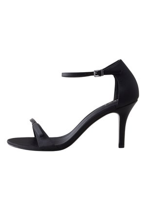 Sandale noire à talon haut avec fine bride à la cheville, bout ouvert et talon aiguille mince sur fond blanc.