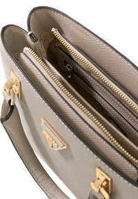 Sac à main structuré beige avec ferrures dorées, matériau texturé et plusieurs compartiments avec fermetures éclair, comprenant un séparateur central.