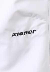 Bílá látka s hladkým povrchem, na které je vyšitý černý logo "ziener". Design je jednoduchý a moderní, zdůrazňuje minimalismus.