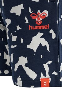 Marineblaue Shorts mit weißen abstrakten Mustern. Verfügt über ein rotes "hummel"-Logo und ein rotes Etikett mit einem Chevron-Design am Saum. Weicher Stoff.
