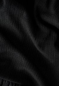 Tissu noir texturé avec une surface froissée, affichant un motif ondulé et une texture douce et durable. Aucun motif ni accent visible.