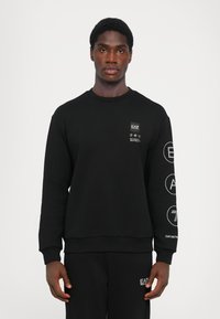 Black sweatshirt featuring a crew neckline, ribbed cuffs, and hem. Brand logo and icons printed in white on the chest and sleeves.