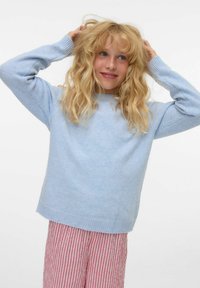 Pull en maille bleu clair avec un col rond et des poignets côtelés, associé à un bas rayé rouge. Le matériau semble doux et texturé.