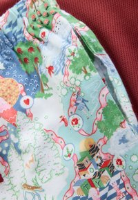 Bawełniane szorty piżamowe z kolorowym nadrukiem krajobrazu z drzewami, sercami i zabawnymi elementami, na teksturowanym bordowym tle.