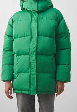 Groene pufferjack met hoge kraag, ritssluiting en contrasterende horizontale stiksels. Voorzien van zijzakken en een gladde, glanzende textuur.