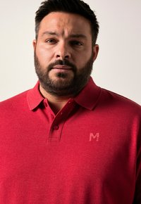 Rode poloshirt van textiel met een gestructureerde stof, voorzien van een knoopsluiting en een reliëflogo op de borst.