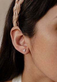 Pendiente de aro en forma de mariposa de color plateado con acentos de cristal. El diseño incluye dos alas más grandes y una piedra central más pequeña.