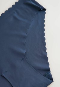Navyblauwe stof met geschulpte randen, gladde textuur, naadloos ontwerp, met stikdetails, die een gebogen zoom en zachte val laat zien.