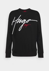 Sweatshirt noir à manches longues, col rond, avec un logo signature blanc à l'avant. Présente une coupe décontractée et un ourlet et des poignets côtelés.