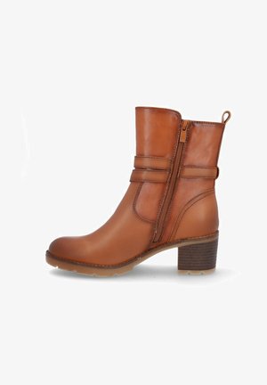 Bota de tobillo de cuero marrón claro con cremallera lateral, detalle de correa, tacón bloque y lengüeta en la parte trasera.