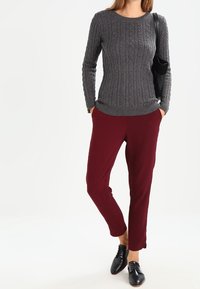 Grå räfflad tröja med rund halsringning, tillsammans med burgunderfärgade smala byxor och svarta snörskor. Enkel design, texturerad tyg.