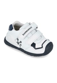 Zapatilla de cuero blanca con acentos en navy, dos correas de velcro, una puntera texturizada y un diseño estampado en el lateral. Suela de goma negra.