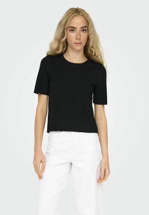 Sort kortærmet cropped t-shirt med rund halsudskæring. Lavet af et blødt, struktureret stof. Kombineret med hvide højtaljede bukser.