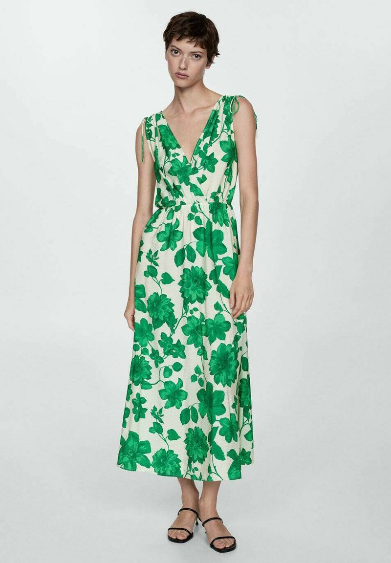 Zelena haljina s cvjetnim uzorkom, dubokim V izrezom, bez rukava i s pojasom u struku. Izrađena od lagane tkanine s prozračnim krojem.