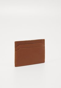 Tarjetero de cuero marrón con textura suave, que cuenta con múltiples ranuras para tarjetas y costuras visibles. Forma compacta y rectangular.