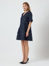 Tamsiai mėlyna trumpa suknelė su tekstūriniu audiniu, turinti nusidėvėjusius kraštus ir subtilius mėlynus akcentus. Suknelė turi V formos iškirptę ir trumpas rankoves.