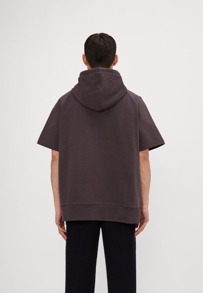 Mørk grå hettegenser med korte ermer, oversized passform og en stor hette. Stoffet ser mykt ut med en jevn tekstur.