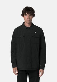 Giacca nera con bottoni realizzata in tessuto leggero. Presenta due tasche sul petto, maniche lunghe e un piccolo logo sul lato sinistro.