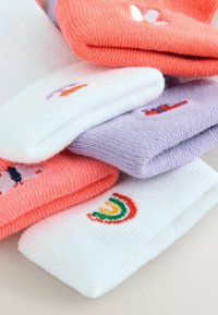 Stak af foldede strikkede sokker i koral, hvid og lavendel med små farverige broderede designs, herunder en regnbue og fugle.