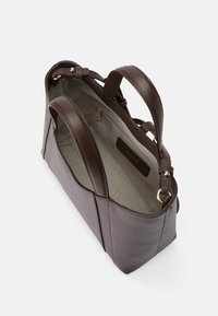 Sacola tote de couro castanho com textura suave, alças duplas, acessórios dourados e um interior espaçoso forrado em tecido claro. Inclui um bolso com fecho.
