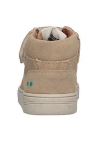 Tan suede hoge sneakers met een klittenbandsluiting, witte rubberen zool en turquoise stippen op de hiel. Zachte textuur, minimalistisch ontwerp.