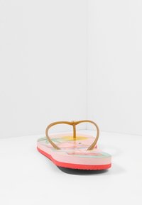 Rosa flip-flop med texturerad sula, ljusbruna plastremmar och ett färgglatt tropiskt mönster på fotbädden. Designad för vardagsbruk.