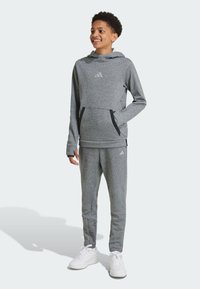 Conjunto deportivo texturizado en gris que incluye un sudadera con capucha y bolsillo canguro, y pantalones ajustados con acentos en negro.