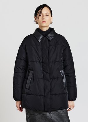 Schwarze Steppjacke mit Steppmuster, Lederakzenten am Kragen und an den Taschen sowie einer legeren Silhouette.