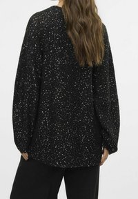 Zwarte trui met lange, oversized mouwen, bedekt met verspreide zilveren pailletten voor textuur en glans. Platte zoom en zacht gebreid materiaal.