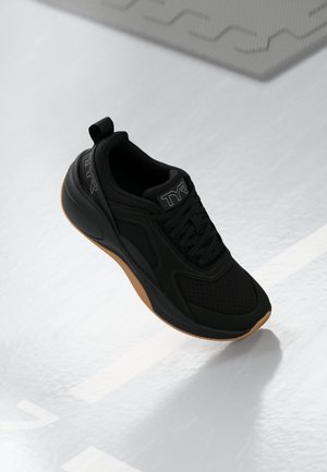 Black athletic shoe with a mesh upper and rubber sole. Features include a rounded toe, lacing system, and a pull tab on the heel.