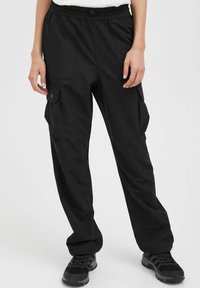 Pantaloni cargo neri con vita regolabile tramite lacci, due tasche laterali e una vestibilità leggermente affusolata; realizzati in tessuto leggero e liscio.