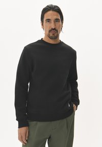 Zwarte katoenen sweatshirt met ronde hals en lange mouwen, met ribgebreide mouwen en zoom; beschikt over een klein logo-opdruk aan de onderzijde aan de linkerzijde.