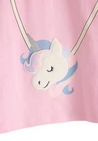 Camicia rosa con un motivo di unicorno, dotata di una testa bianca pelosa, corno argentato glitterato e criniera pastello blu e rosa. Contorni neri accentuano il design.