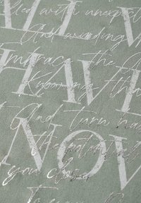 Teksturowana tkanina w stonowanej zieleni, z białymi i srebrnymi, pięknie pisaną oraz wyraźną czcionką, zawierająca abstrakcyjne frazy, tworząc warstwowy efekt wizualny.