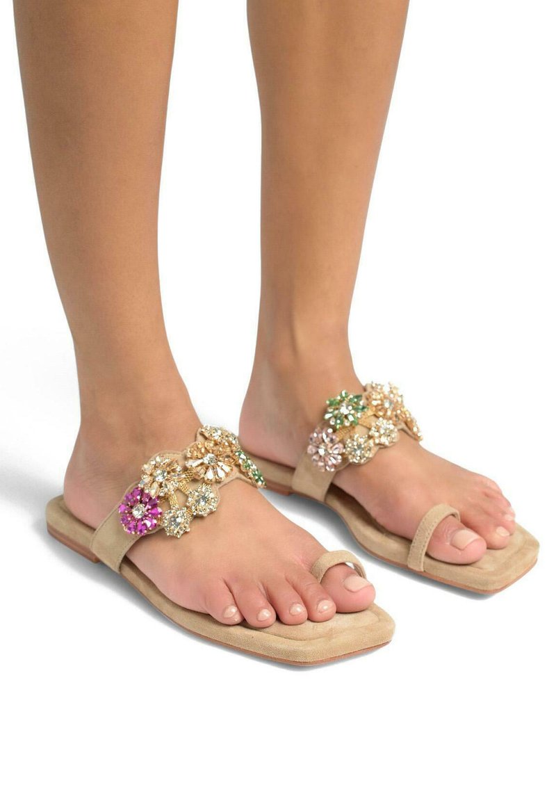 Beige flache Sandalen mit dekorativen floralen Verzierungen in Pink, Grün und klaren Kristallen. Weiche Wildleder-Textur und minimalistisches Design.