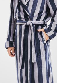 Accappatoio a righe in navy e grigio, realizzato in tessuto morbido. Presenta una cintura da annodare, tasche e colletto a scialle. Motivo a righe verticali.