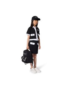 Σετ κοντομάνικου πουκάμισου και φούστας σε ασπρόμαυρο με τσέπες· κορίτσι φοράει μαύρο καπέλο, κρατάει μαύρο σακίδιο με λευκές λεπτομέρειες και παπούτσια.