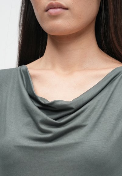 Top cinza drapeado, feito de tecido macio, apresentando um design de gola de cowl e uma textura suave, destacando a área do decote.