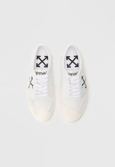 Bílé plátěné tenisky se černým brandingem Off-White. Mají hladký povrch, ploché tkaničky a gumovou podrážku s krémovými akcenty.