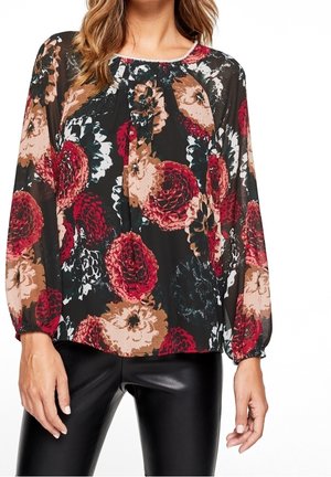 Blouse florale en tissu transparent noir avec de grandes fleurs rouges, oranges et crème, décolleté en scoop, et manches longues froncées.